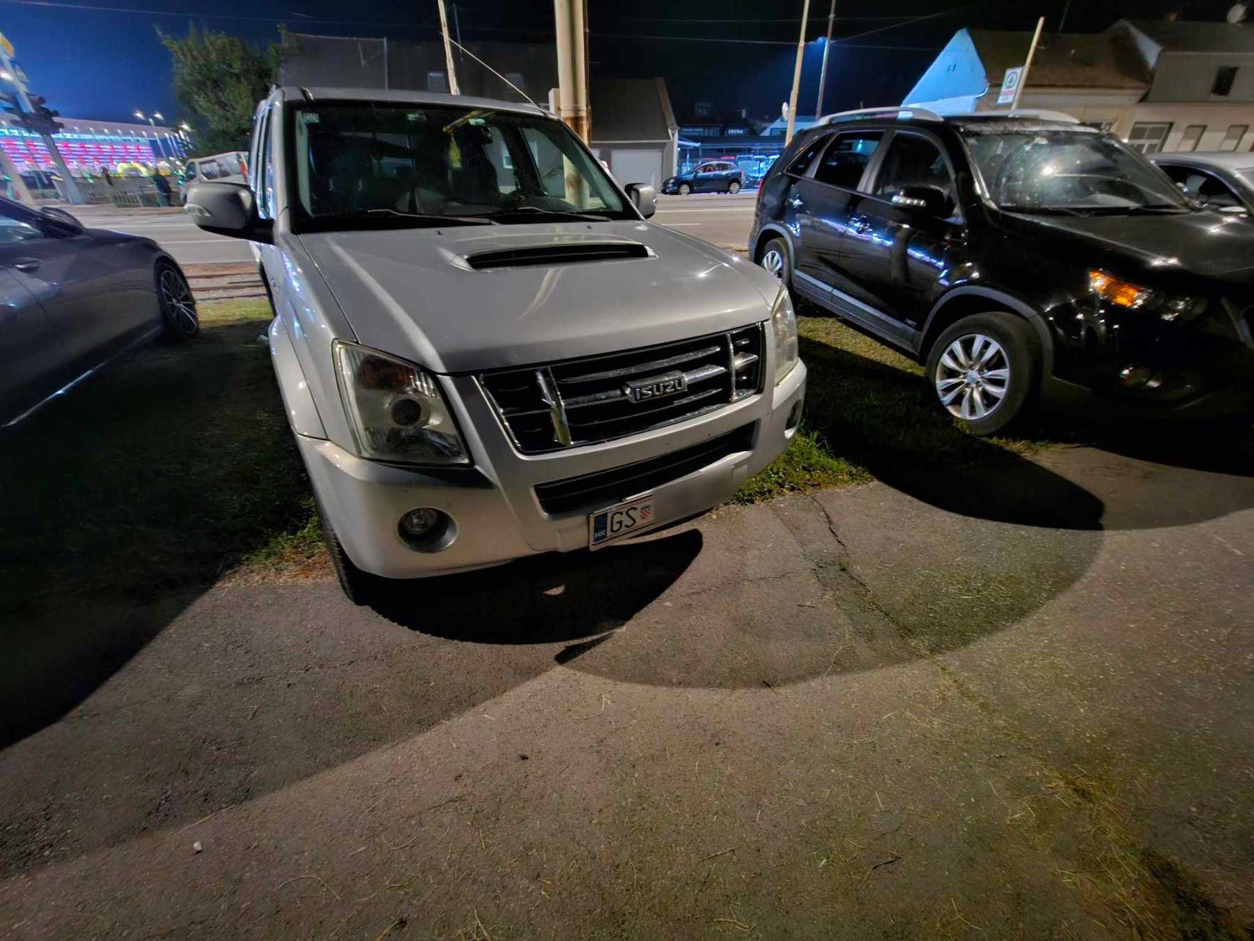 Automobili parkirani na zelenoj površini kod stadiona
